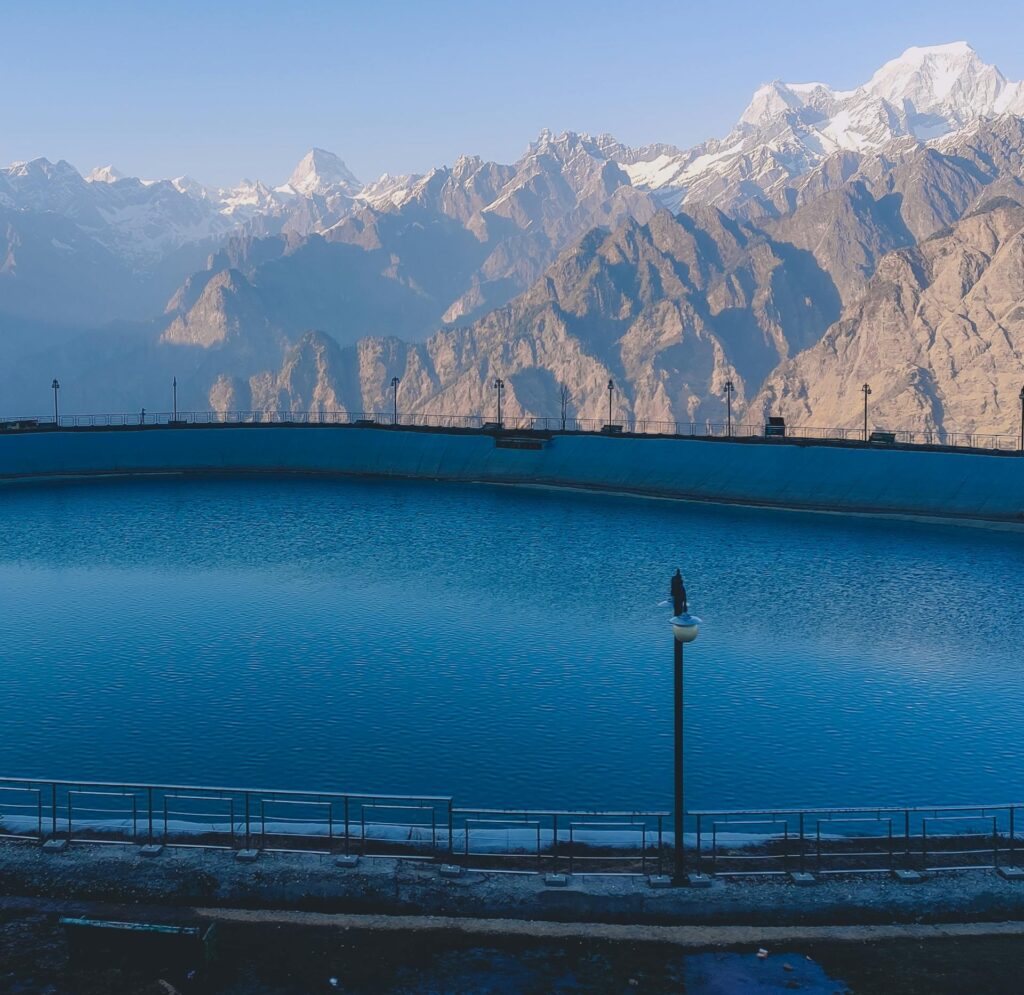 Auli’s Artificial Lake – A Peaceful Spot with Stunning Mountain Views Calm, blue waters of Auli’s Artificial Lake set against the dramatic backdrop of snow-covered Himalayan peaks in Uttarakhand, India.