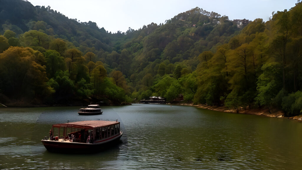 Tourist boats on a serene lake surrounded by lush green forested hills at Hidimba Parvat near Bhimtal, Uttarakhand