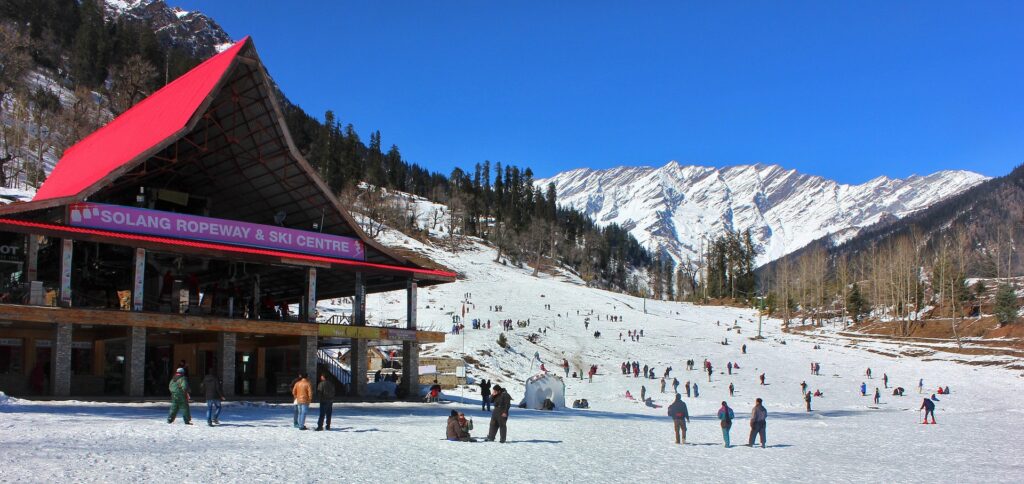 Solang Valley Ropeway & Ski Centre – Your Gateway to Snow Adventures Hub in Manali Tourists enjoying snow activities at Solang Ropeway & Ski Centre in Manali, with a backdrop of the majestic snow-covered Himalayas.