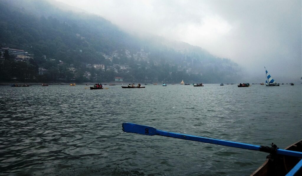 Boating on Naini Lake in Nainital surrounded by misty hills and lush greenery
