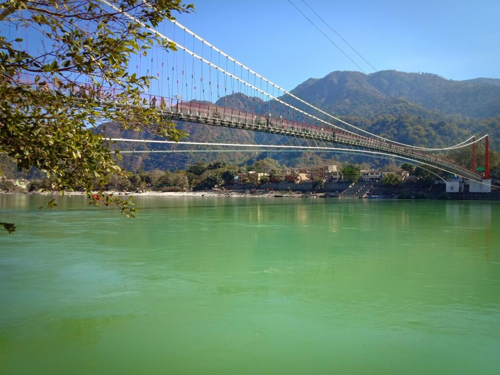 Suspension bridge over the Ganges River in Rishikesh with Himalayan hills in the background on a clear day