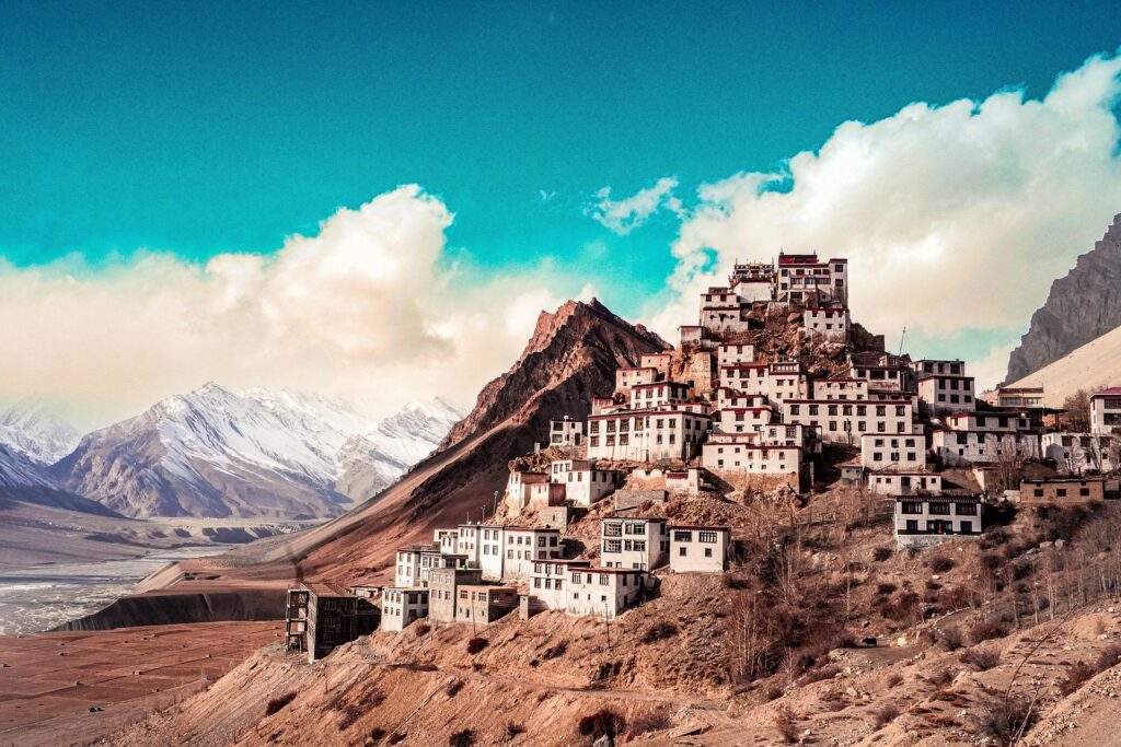 "Key Monastery in Spiti Valley – A Timeless Himalayan Buddhist Retreat Surrounded by Majestic Mountains" Key Monastery perched on a hilltop in Spiti Valley with snow-capped Himalayan mountains in the background under a vibrant blue sky.